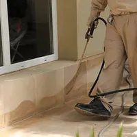 General pest control technician spraying exterior perimeter around a home in Bellevue, WA