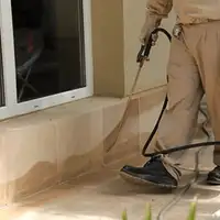 General pest control technician spraying exterior perimeter around a home in Bellevue, WA
