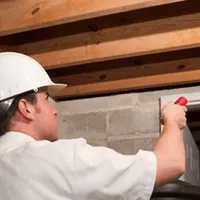 Termite inspection technician checking a basement wall and framing for termite activity in Bellevue, WA