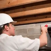Termite inspection technician checking a basement wall and framing for termite activity in Bellevue, WA